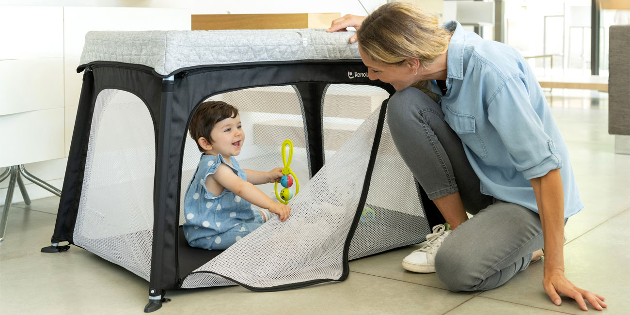 mother with baby playing in a travel cot playpen with opening side